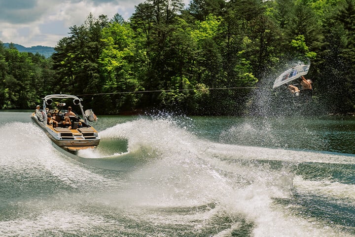 A wakeboarder jumps behind a white and gold 2025 Malibu Wakesetter 23 LSV