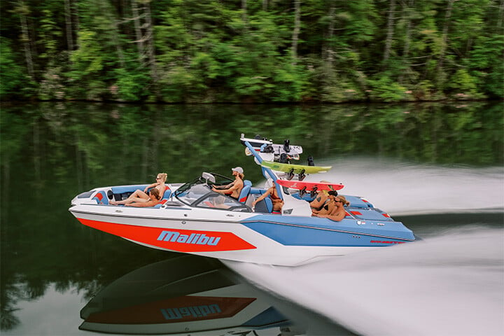 Red, White, and Blue 2025 All-New Malibu Boats Wakesetter 24 MXZ cruising down a smooth lake