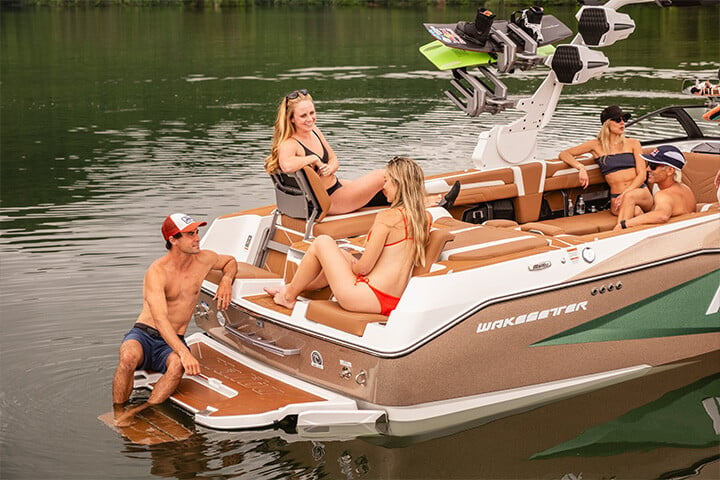 Friends conversing on the back of a green, gold, and white All-New 2025 Malibu Wakesetter 25 LSV while sitting in the Max-Relax™ Sundeck Loungers