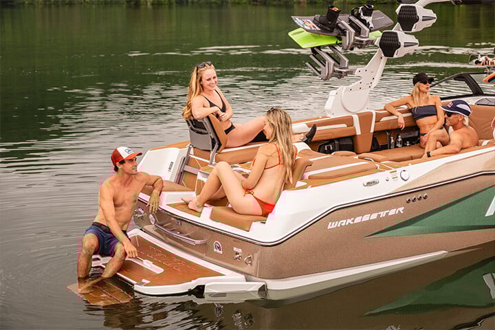 Friends conversing on the back of a green, gold, and white All-New 2025 Malibu Wakesetter 25 LSV while sitting in the Max-Relax™ Sundeck Loungers Friends conversing on the back of a green, gold, and white All-New 2025 Malibu Wakesetter 25 LSV while sitting in the Max-Relax™ Sundeck Loungers