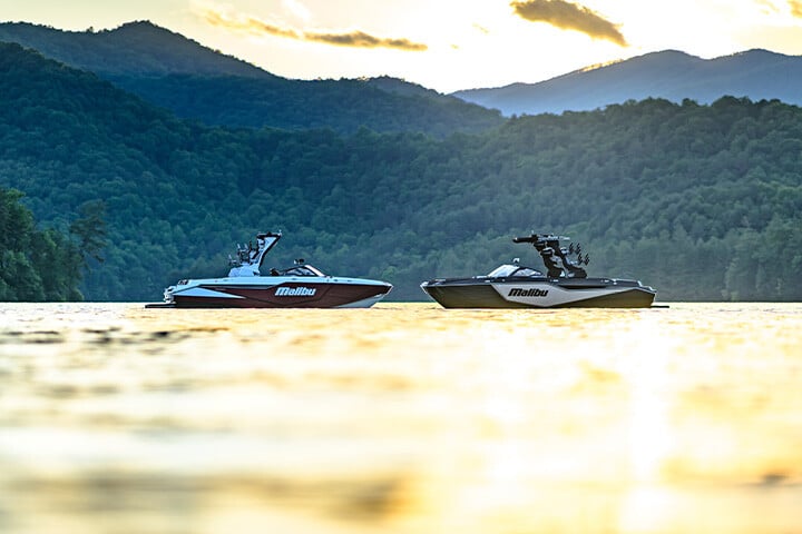 Malibu M230 and M242 sitting bow to bow in front of mountains Malibu M230 and M242 sitting bow to bow in front of mountains