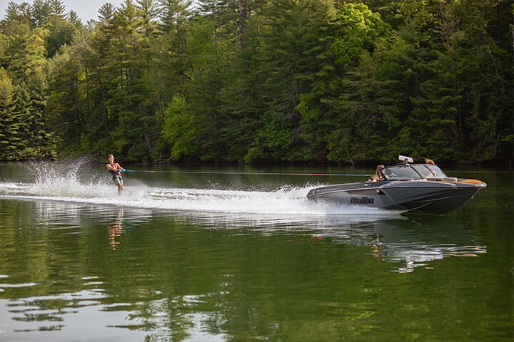 A black and gray Malibu TXi Response pulling a slalom skier A black and gray Malibu TXi Response pulling a slalom skier