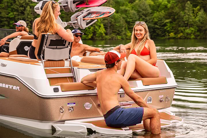 Friends lounging on the stern of a green, gold, and white All-New Malibu Wakesetter 25 LSV Friends lounging on the stern of a green, gold, and white All-New Malibu Wakesetter 25 LSV