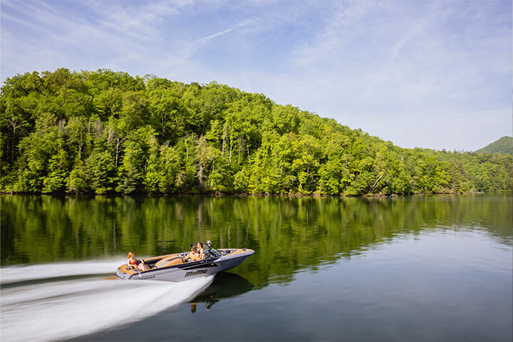 A gray and black Malibu TXi Response cruising down the lake on a sunny day