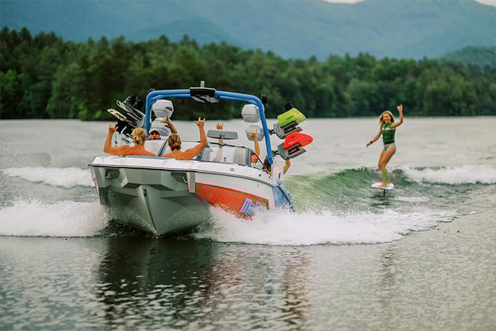 Someone Wakesurfing Behind a Red, White, and Blue 2025 All-New Malibu Wakesetter 24 MXZ Someone Wakesurfing Behind a Red, White, and Blue 2025 All-New Malibu Wakesetter 24 MXZ