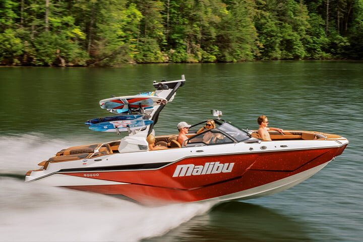 A red, white, and black All-New 2025 Malibu M230 cruising on the lake on a sunny day