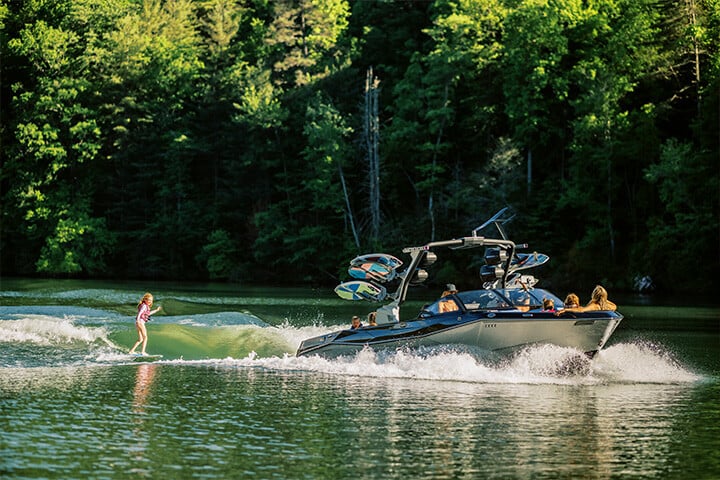 Child wakesurfing behind a black and silver 2025 Malibu Wakesetter 26 LSV.